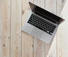 Poster - Top view of laptop on loft-style table in sunny day. Coworking or working at home concept image.