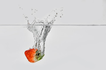 Wall Mural - ripe red strawberries splashing into clear transparent water