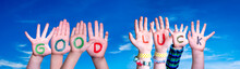Kids Hands Holding Colorful English Word Good Luck. Blue Sky As Background