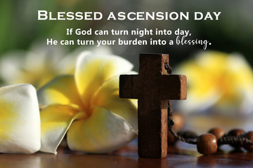 Blessed ascension day. God can turn your burden into a blessing as He can turn night into day. Ascension day of Jesus Christ message concept with holy cross crucifix closeup, rosary beads and flowers.