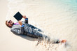 © PeskyMonkey - Barefoot businessman relaxing with a tablet computer on the shore of a tropical beach with waves breaking over his suit
