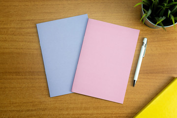 Stationery set with two colored empty notebooks one pink and one purple and a white empty pen for mockup purposes