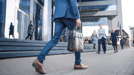 close up leg shot of a businessman in a suit commuting to the office on foot. he's carrying a leathe