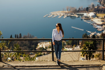 Wall Mural - Traveller at the top peak of Monte San Salvatore in Lugano, Switzerland. Overlooking the lake town. Young girl looking at the panoramic scenery. Young girl admiring the alpine landscape. Copy space.