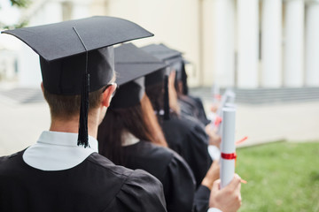 Wall Mural - Graduates with diplomas in front of the university.