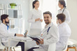© Studio Romantic - Male doctor sitting at a table with collegues in white lab coats at a medical hospital.