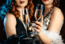 Close Up Glasses Of Champagne. Flappers Women Wearing In Style Of Roaring Gatsby Twenties Drinking Alcohol. Vintage, Retro Party, Fashion, Girls Friends Concept