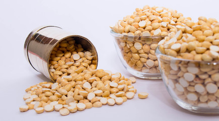 Group of a healthy roasted gram in a bowl with brass measuring jar on a white background