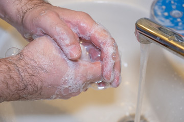 Personal hygiene and prevention of the coronavirus pandemic wash men's hands with soap and water.