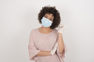 Sticker - Image of cheerful pretty young caucasian lady standing against gray wall with hand near face. Looking with glad expression at the camera after listening to good news. Confident girl.