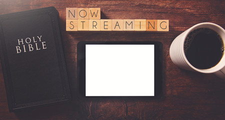 Sticker - Now Streaming in Block Letters on a Wooden Table with a Holy Bible