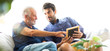 © NVB Stocker - Father and son family time together at home concept. Happy old father and son sitting together and looking photos while remembering old times past.