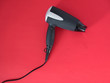 Black hair dryer isolated on red background. Electric hair dryer