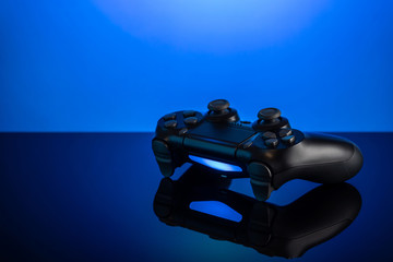 Sticker - Black gamepad with backlight on blue back. Joystick on glossy surface.