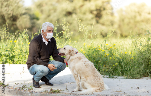 senior man in mask with his pet dog on street because of air pollution and epidemic in city. Protection against virus, infection.Concept relationships with animals during quarantine