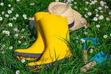 Fototapeta  - Gardening time with yellow boots, straw hat and gardening tools