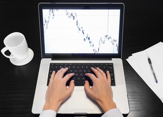 Person at desk working on office computer looking at stock chart. Stock market trading concept. 