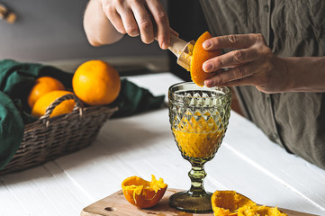 Woman making orange juice at home. Preparation of orange juice. Health concept. Soft focus