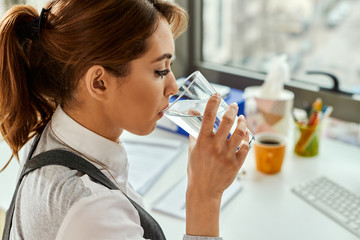 Wall Mural - Businesswoman having a glass of water while working un the office.