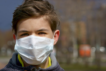 teen in a medical mask on the street in the city