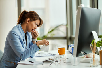 Wall Mural - Young businesswoman coughing while working in the office.