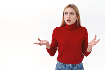 Beauty, women and fashion concept. Confused and frustrated blond young woman look around cant understand what happening, raise hands in dismay gasping worried, white background