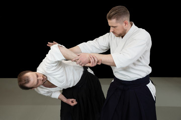 Wall Mural - A young man makes a painful hand technique from aikido technique in a dojo