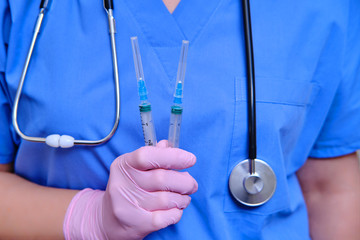 A doctor in a blue uniform with syringes in his hand, close-up. Medic with coronavirus vaccine, concept of medication for flu virus