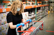 © Ursula Page - A woman shopping for groceries and necessities for her family inside a warehouse-style store during the pandemic Covid-19 coronavirus pandemic and she is wearing a face mask and latex rubber gloves