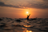silhouette of a man surfing at sunset in the ocean