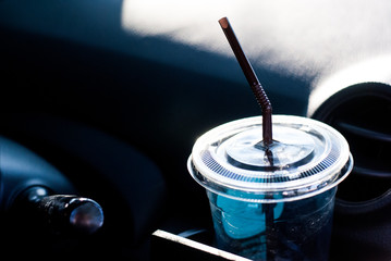 Plastic take away coffee cup is put in the drink slot in the car near steering wheel