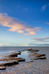 Wall Mural - Stunning colorful sunrise over ocean landscape scene with cliffs and beautiful cloud formations