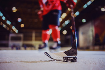 Close up of hockey stick and puck. Hockey player holding a stick. Selective focus on puck.