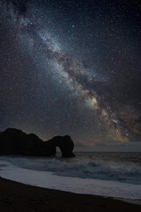 Wall Mural - digital composite of milky way over majestic seascape landscape image of cliffs and archway