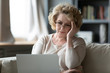 © fizkes - Old woman sit on couch using laptop looks at screen feels stressed not understand need assistance with new app, wrong password, exhausted, older generation and difficulties with modern tech concept