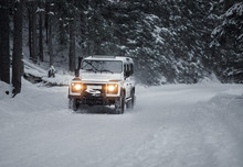 Vintage Sport Utility Vehicle Driving During Snow Storm In Forest