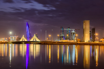 Wall Mural - Beautiful view of iconic building Bahrain World Trade Center and Shaikh Isa Bin Salman Causeway Bridge at blue hour after sunset with striking clouds, Manama, Bahrain