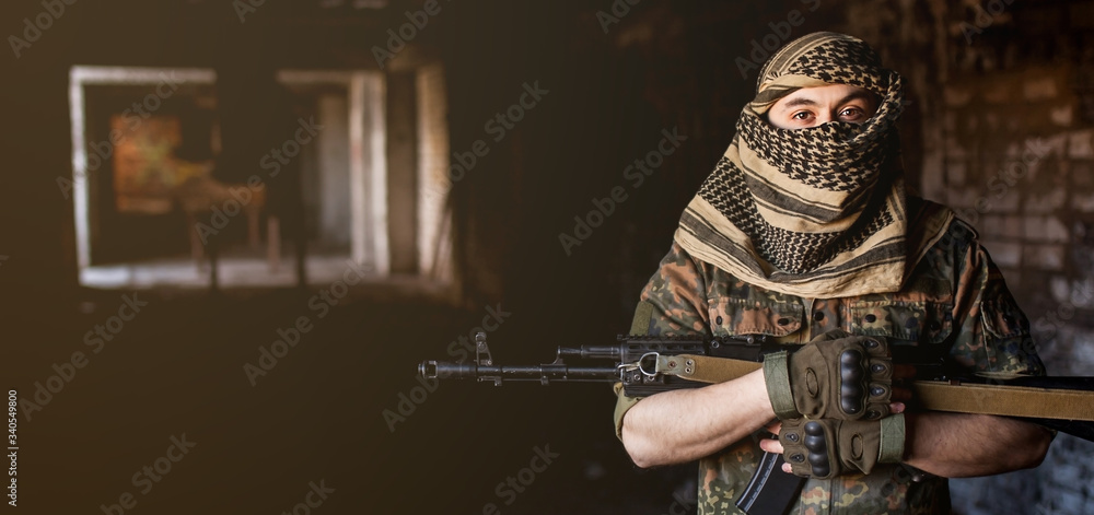 Arab male soldier in a headdress from the national keffiyeh with a weapon in his hands Muslim man with a gun on a black background - obrazy, fototapety, plakaty 
