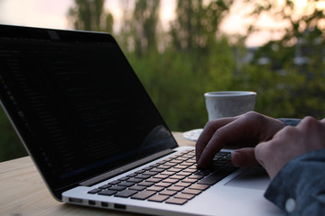 man, businessman, programmer, working in the evening at a laptop on the balcony of his house, hands 