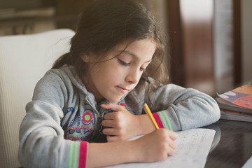 Wall Mural - Seven years old girl doing homework at home