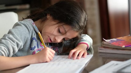 Wall Mural - Seven years old cute girl doing homework at home alone