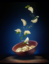 Hot Pierogi Flying Out Of The Clay Bowl With Cream And Parsley. Some Vareniki Stay Inside The Plate.  Blue Background.