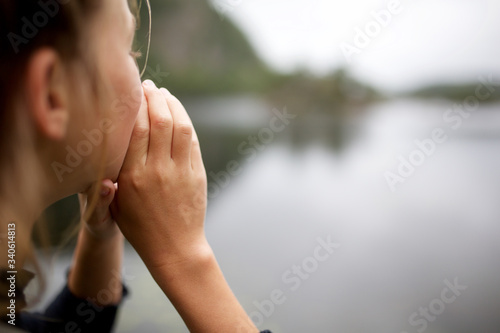 girl shouting by lake with hands to mouth