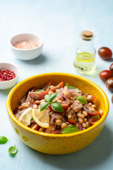 Wall Mural - Healthy salad with tuna, white beans, cherry tomatoes, red onion and basil leaves in ceramic bowl on concrete background