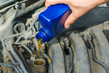 Close up photo of a male hand fill a car engine by oil.