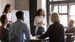 © fizkes - Smiling multicultural diverse colleagues brainstorm discuss financial ideas at meeting in boardroom, happy multiethnic coworkers employees talk consider flip chart presentation at briefing together