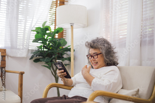 Senior woman old sitting on couch using smartphone browsing, online shopping or video call chat with family. stay safe at home preventing Coronavirus outbreak crisis. aged people connecting technology