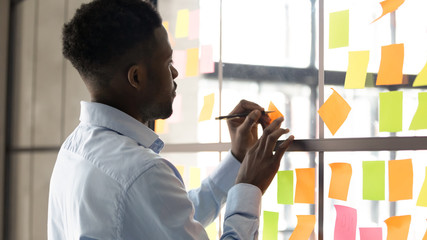Wall Mural - focused african american male employee write on colorful sticky notes develop business project in of