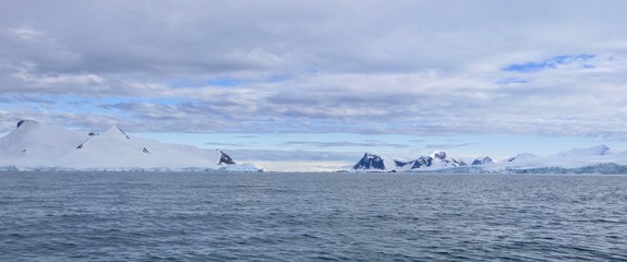 Mountains in antarctic sea with snow, ice and blue cloudy sky, Antarctica