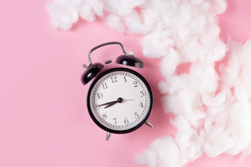 alarm clock on pink background with cloaks